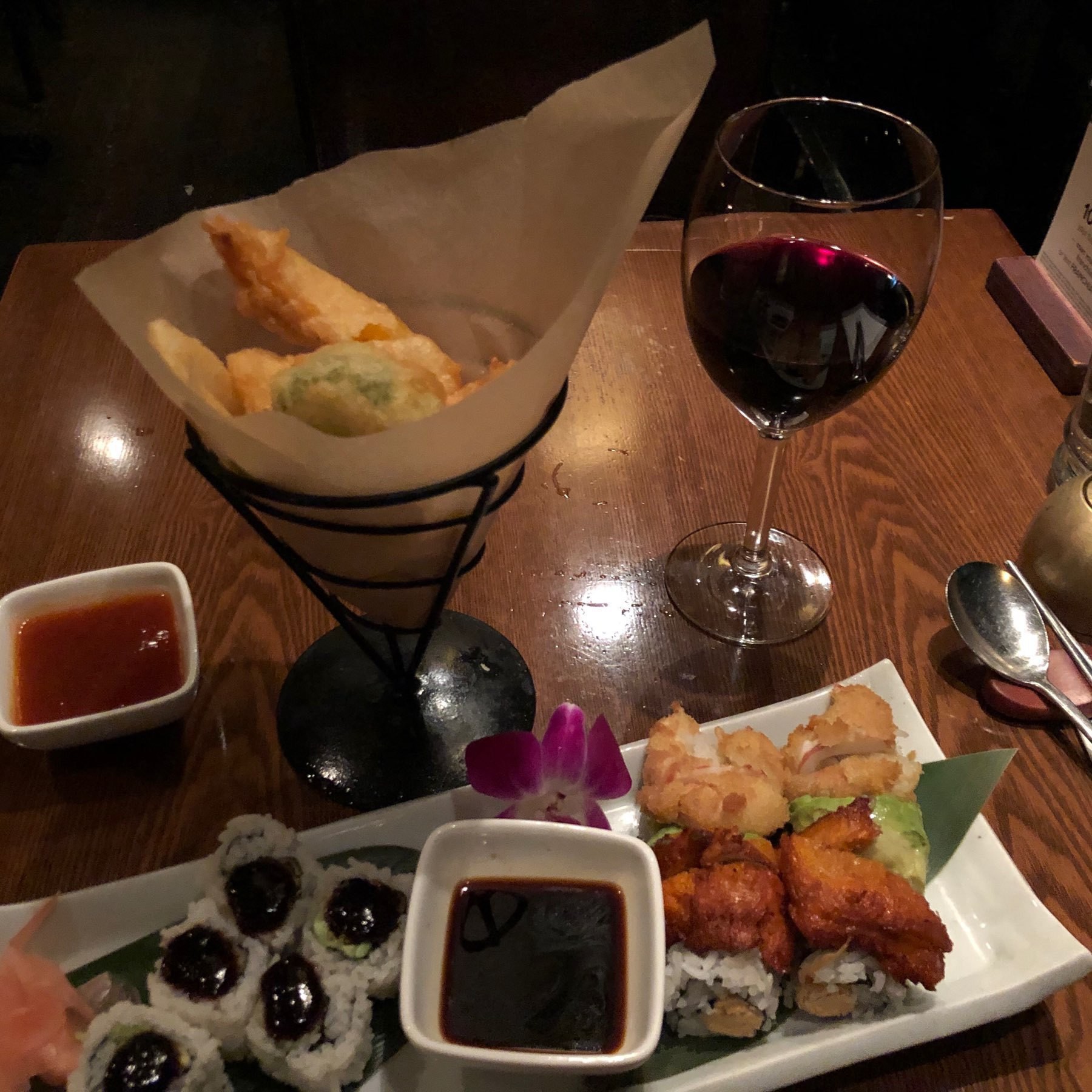Platter eith vegatarian sushi, glass of red wine, and a cone filled with fried vegetables.