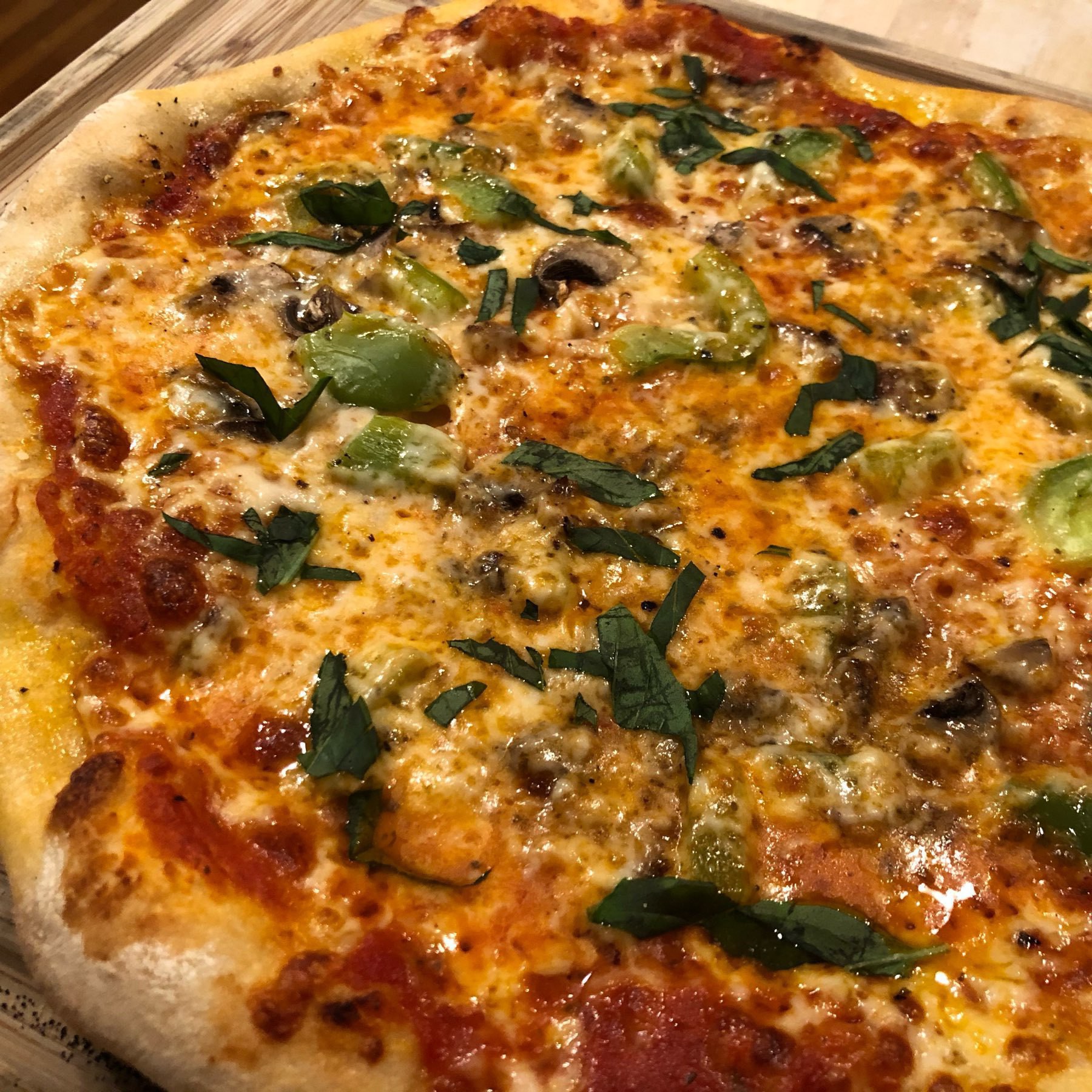 Fresh-baked pizza with bell pepper, mushroom, and basil.