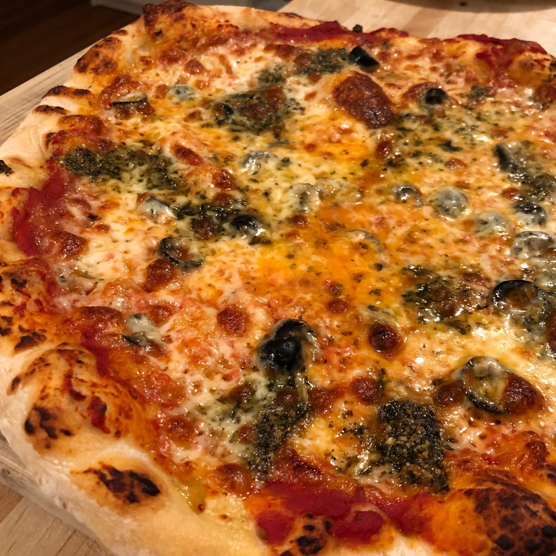 Home-baked pizza with cheese, pesto, olives, tomato sauce.