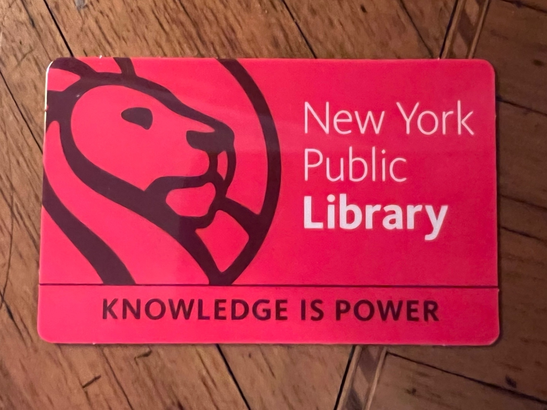 Red card with lion illustration and words: “New York Public Library” and “Knowledge is Power.”