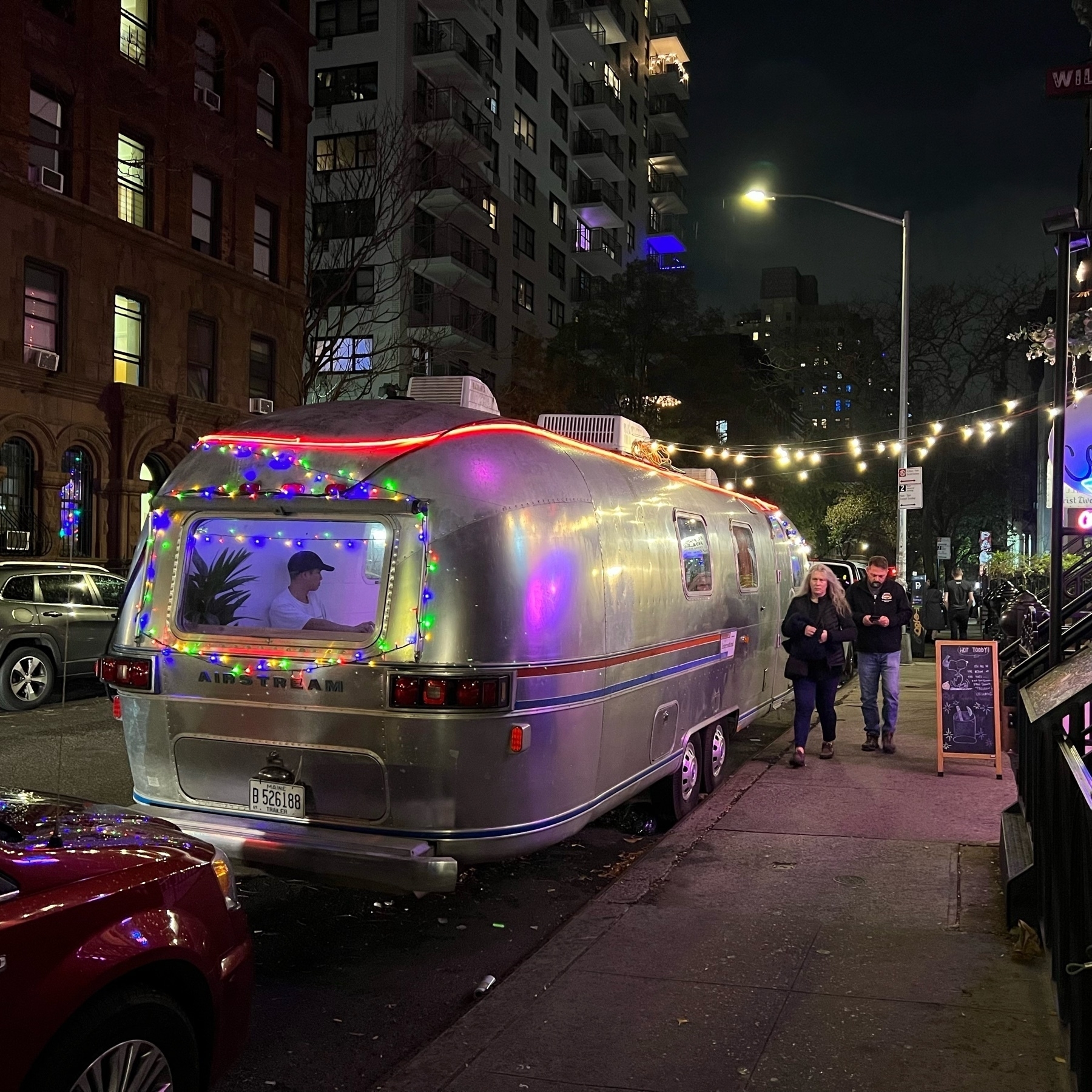 A metal streamline camper parked on a city street to serve as outside ding room