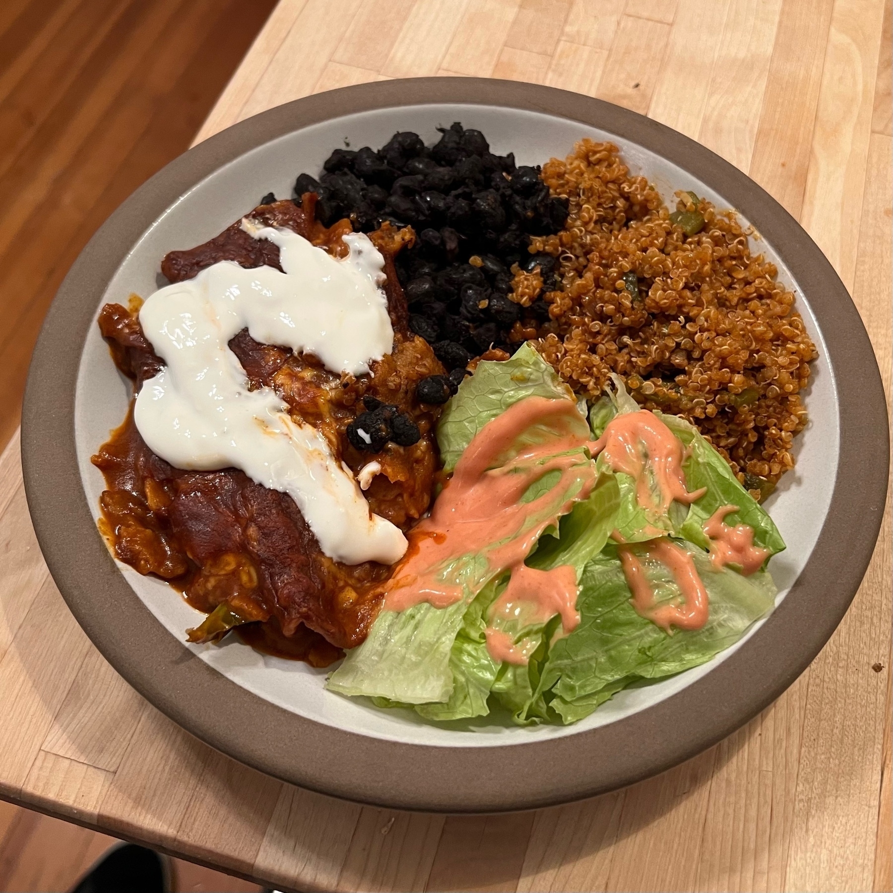 picture of a dinner plate with black beans, enchiladas with sour cream, quinoa seasoned like mexican rice, and a plain salad with thousand island dressing
