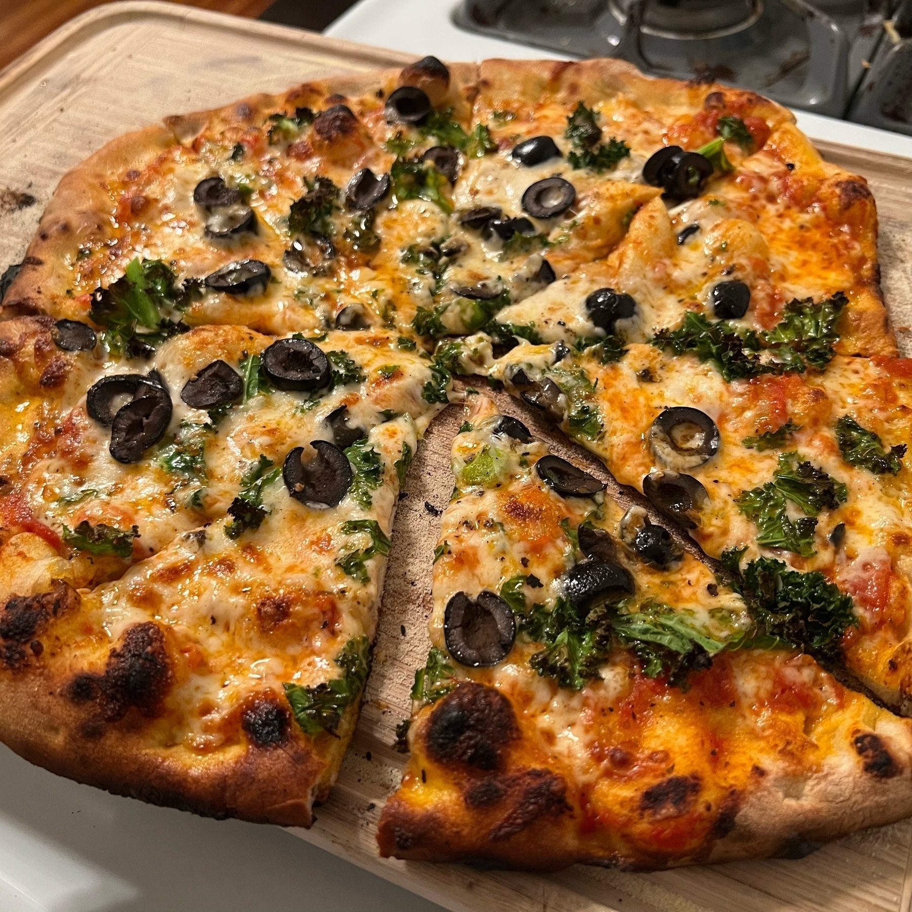 homemade pizza with black olives and kale